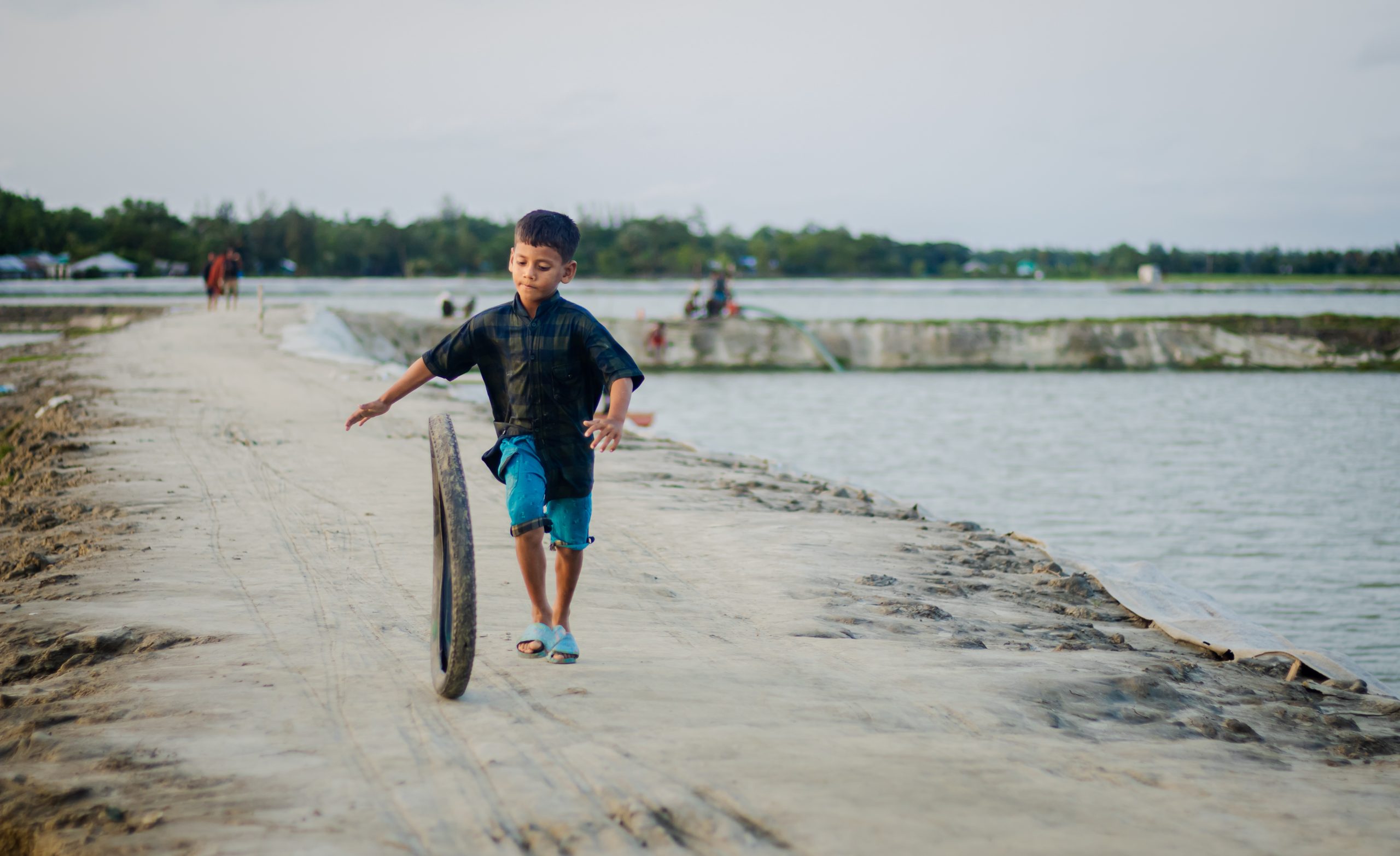 Joy in simplicity — a boy’s timeless game by the riverbank.